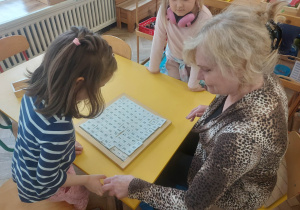 Zdjęcie przedstawia kobietę i dziewczynkę, przy tablicy do 100.