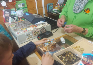 Zdjęcie przedstawia pierwsze zakupy dzieci w sklepie i liczenie pieniążków