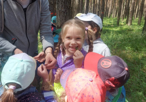 Zdjęcie przedstawia nauczyciela, który pokazuje jadalne rośliny, które można znaleźć w lesie