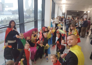 Zdjęcie przedstawia duży korytarz, na którym znajdują się dzieci, nasza wolontariuszka i nauczyciele. Szykujemy się do występu.