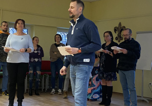 Zdjęcie przedstawia mężczyznę mówiącego swoją rolę, z kartką w ręku.