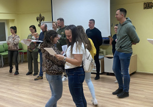 Zdjęcie przedstawia grupę rodziców podczas próby, wymieniających się spostrzeżeniami.