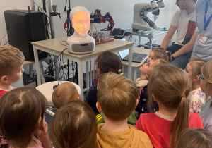 Zdjęcie przedstawia dzieci rozmawiające z robotem.
