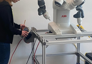 Zdjęcie przedstawia kobietę sterującą robotem.