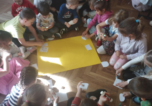 Na zdjęciu widzimy dzieci, które segregują i przyklejają na żółty karton dobre i złe zachowania ludzi względem środowiska.