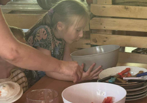 Zdjęcie przedstawia dziewczynkę zaglądającą do miski.