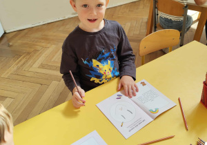 Chłopiec pracuje przy stoliku.