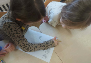 Zdjęcie przedstawia dzieci ozdabiające kartkę