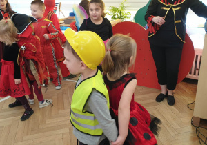 Zdjęcie przedstawia dzieci przebrane w stroje karnawałowe. Dzieci tańczą przyklejone do siebie plecami.
