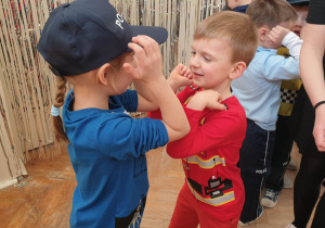 Zdjęcie przedstawia dzieci przebrane w stroje. Dzieci tańczą dotykając się łokciami.