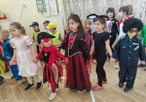 Zdjęcie przedstawia tańczące dzieci. Dzieci przebrane są w stroje karnawałowe.