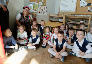 Zdjęcie przedstawia dzieci i nauczycielkę i pozujących do zdjęcia. Wszyscy przebrani są na ludowo.