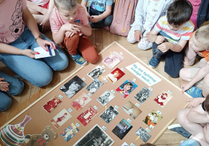 Zdjęcie przedstawia dzieci oglądające zdjęcia przypięte do tablicy.