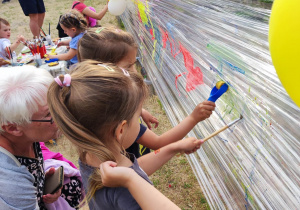 Zdjęcie przedstawia dzieci malujące na folii.