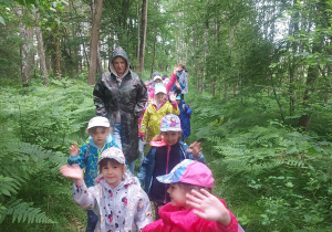 Na zdjęciu widać grupę dzieci wędrującą przez las