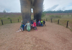 Na zdjęciu widać w jaki sposób dzieci mierzą obwód nogi dinozaura