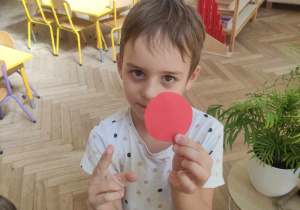 Zdjęcie przedstawia chłopca, który pokazuje znalezioną czerwoną kropkę.