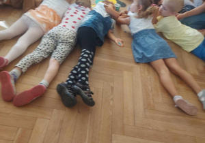na zdjęciu widać dzieci leżące na podłodze podczas ćwiczenia relaksacyjnego