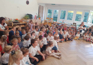 Zdjęcie przedstawia dzieci i nauczycieli zebranych w jednej sali.