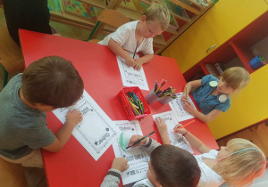 Dzieci wyklejające wydarte elementy z papieru kolorowego.