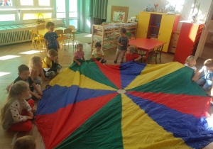 Dzieci podczas zabawy w koloryz wykorzystaniem chusty animacyjnej.