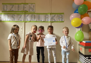 Pięcioro dzieci stoi i pozuje do zdjęcia z kartką z napisem" Jestem przedszkolakiem jaka jest twoja super moc."