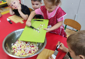 Dzieci wkładają pokrojone składniki do wspólnej miski