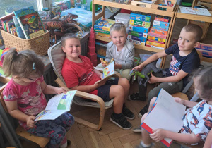Zdjęcie przedstawia dzieci siedzące w kąciku z książkami.