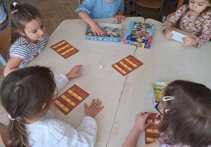 Zdjęcie przedstawia dzieci grające w grę planszową.