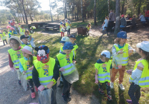 Zdjęcie przedstawia dzieci podczas sprzątania lasu