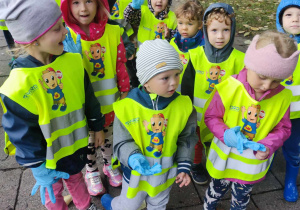 grupka dzieci ubrana w kamizelki odblaskowe i gumowe rękawiczki