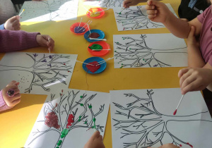 Dzieci malując patyczkami do uszu wykonują pracę plastyczną "Jesienne drzewo"