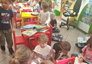 Na zdjęciu widzimy, jak grupka dzieci ogląda książki o różnej tematyce.
