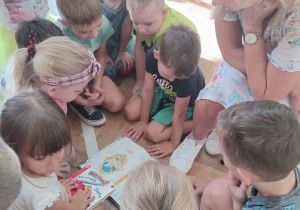 Dzieci oglądają ilustracje w książce.