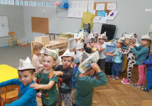 Dzieci z czapkami z gazet na głowach.