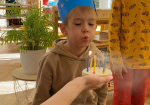 Zdjęcie przedstawia chłopca zdmuchującego świeczki.