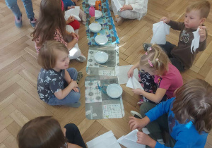 Zdjęcie przedstawia grupę dzieci, które tworzą masę papierową do malowania