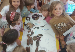 Na zdjęciu widać grupę dzieci, która pokazuje swój jesienny obraz wspólnie wykonany