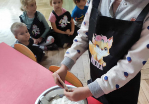 Dziewczynka przygotowuje śmietanę z cukrem waniliowym no klusek