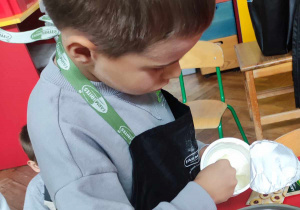 Chłopiec przygotowuje śmietanę z cukrem waniliowym no klusek