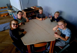 Zdjęcie przedstawia dzieci siedzące przy stole i jedzące galaretkę.