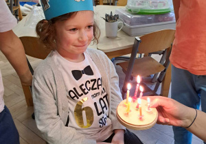 Zdjęcie przedstawia chłopca przy torcie ze świeczkami.