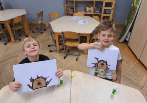 Zdjęcie przedstawia dwóch chłopców, prezentujących swoje prace.