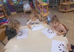 Zdjęcie przedstawia dzieci rozdmuchujące farbę przy pomocy rurek.