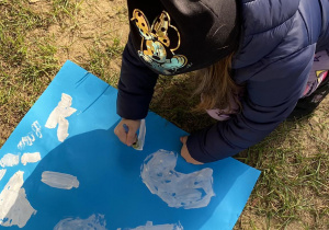 Dziecko maluje swoją chmurę na niebieskim tle.
