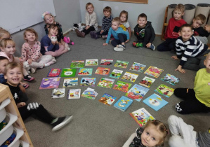 Na zdjęciu widzimy dzieci z grupy I oraz położone na dywanie książki, które będą wybierać.