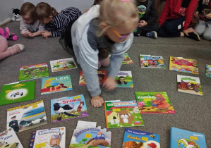 Na zdjęciu widzimy dziewczynkę, która wybiera książkę z Biblioteczki grupowej.