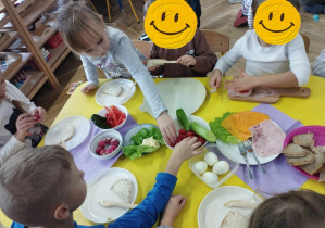 Na zdjęciu widzimy grupkę dzieci, które samodzielnie wykonują kolorowe, zdrowe kanapki.