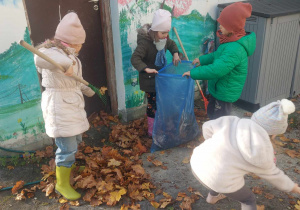 Na zdjęciu widać dzieci sprzątające taras z liści