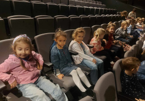 Na zdjęciu widać grupę dzieci siedzących na widowni oczekujących na spektakl